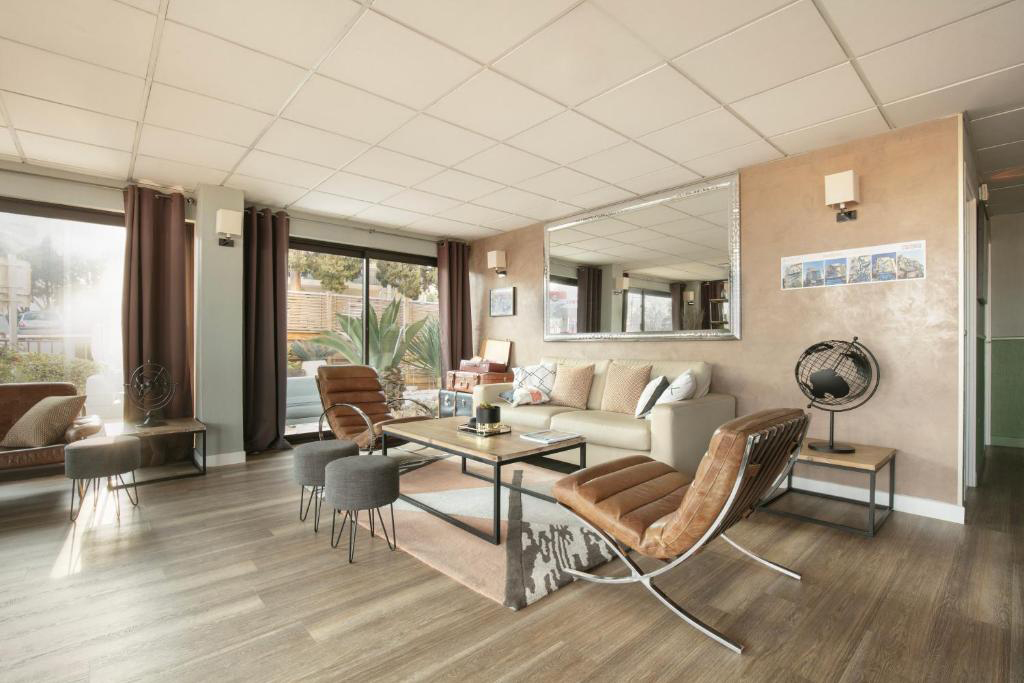 Bright, modern lobby at Hotel Le Collier with armchairs, a coffee table, and large windows letting in natural light.