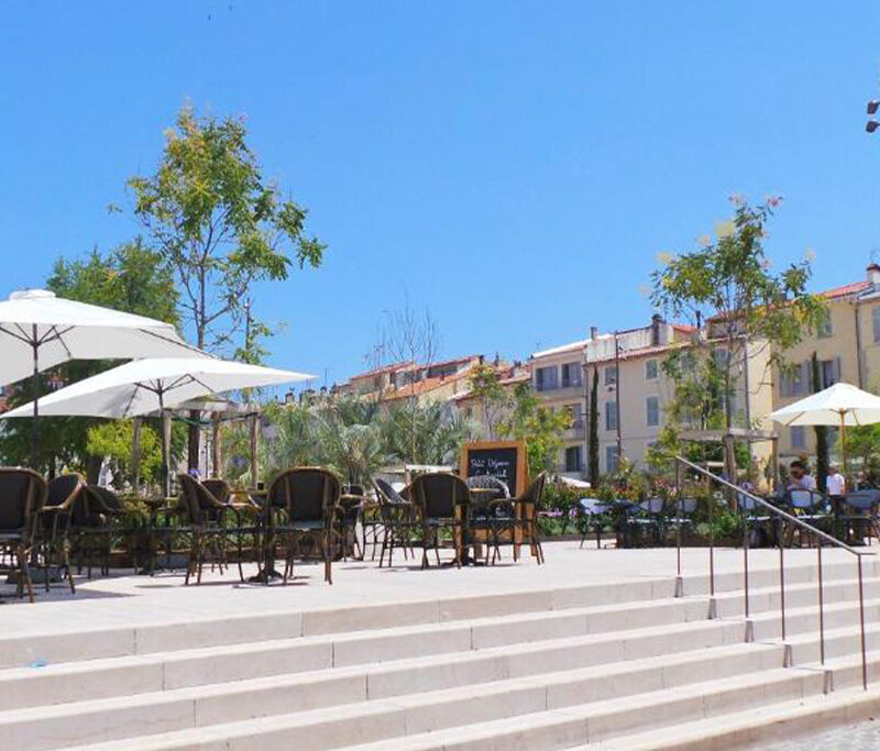 Hotel Relais du Postillon exterior showing a stepped plaza with shaded seating and trees in a lively Antibes setting.