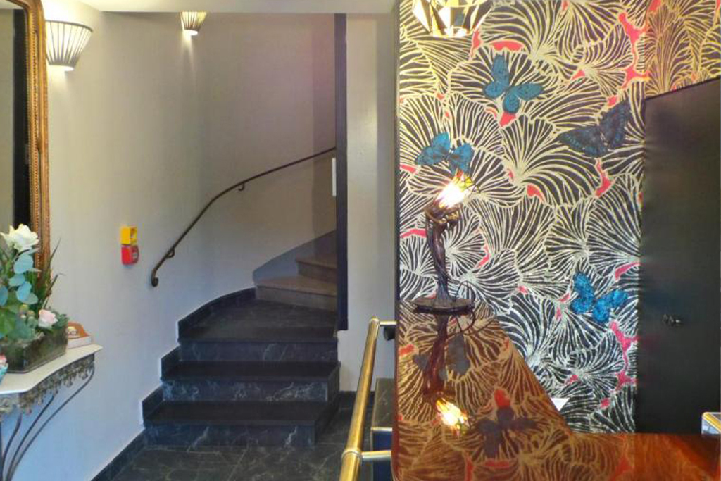 Charming lobby at Hotel Relais du Postillon with floral motifs, a staircase, and vintage‑style accents.